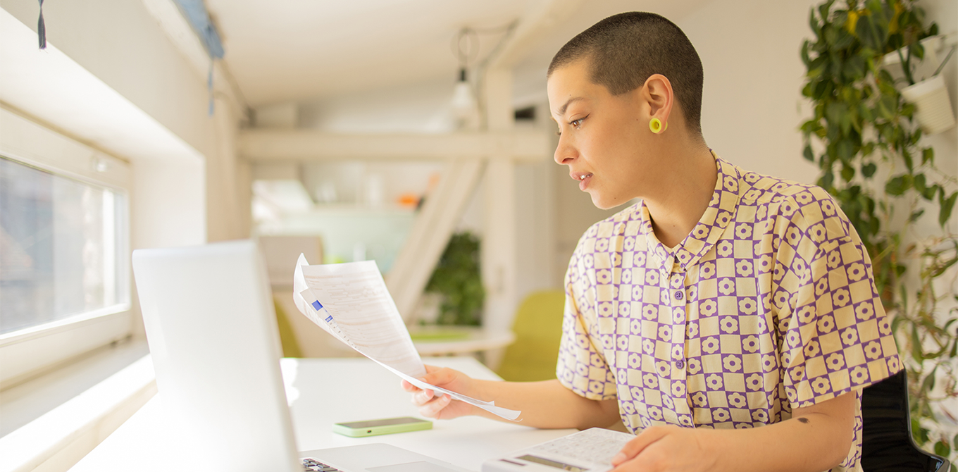 a woman looking at paperwork and her computer